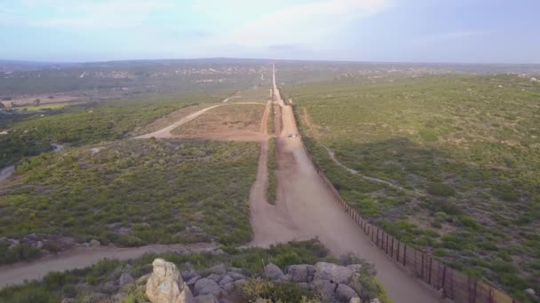 アメリカの国旗は カリフォルニア砂漠のメキシコ国境の壁の上を飛ぶ — ストック動画