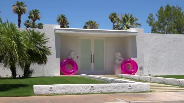 カリフォルニア州パームスプリングスにあるピンクのインナーチューブが入った古典的なミッド世紀のモダンなデコスタイルの家のショットを確立する方法 — ストック動画