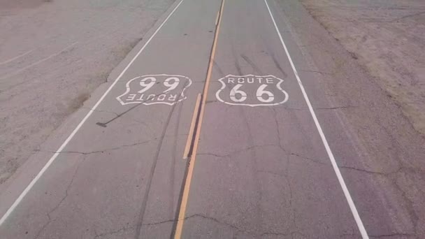 アリゾナ州の孤独な砂漠の高速道路の上空をドローン66号線が舗装され下を通る車が描かれています — ストック動画
