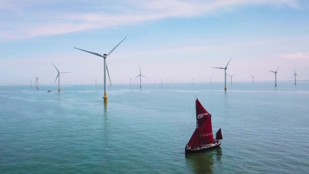 多くの風力タービン風車の中で フラット底の帆船がイギリスのテムズ川河口を上ります — ストック動画