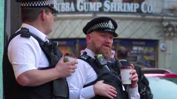 Dwóch Policjantów Pije Kawę Obserwuje Pieszych Ruchliwej Dzielnicy Turystycznej — Wideo stockowe