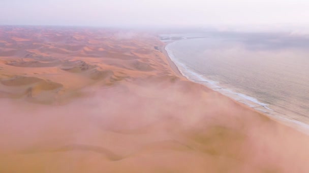 ナミビアのスケルトン海岸沿いのナミブ砂漠の広大な砂丘の上に雲と霧を通して良い高い空中ショット — ストック動画