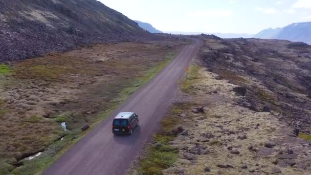 北西フィヨルドのアイスランドの未舗装道路を走行する黒いキャンパーバンの上に空中上昇 — ストック動画