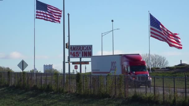 長距離トラッカーはアメリカの州間高速道路に沿って予算ホテルとアメリカの旗を渡します — ストック動画