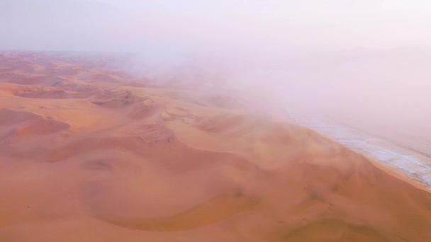 ナミビアのスケルトン海岸沿いのナミブ砂漠の広大な砂丘の上に雲と霧を通して良い高い空中ショット — ストック動画