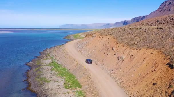 在冰岛西北部峡湾劳迪森杜尔海滩附近的一条土路上行驶的一辆黑色面包车的上空 — 图库视频影像