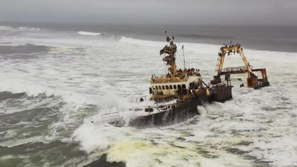 ナミビアのスケルトン海岸沿いの不気味な難破船に囲まれた釣りトロール船の上に劇的な航空機 — ストック動画