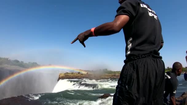 滝の端に近いザンビアのビクトリア滝の端にある悪魔のプールに飛び込む男 — ストック動画