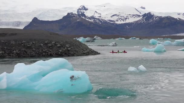 ケイカーズはアイスランドのジョクルサロンの融解氷河ラグーンを通って移動します — ストック動画