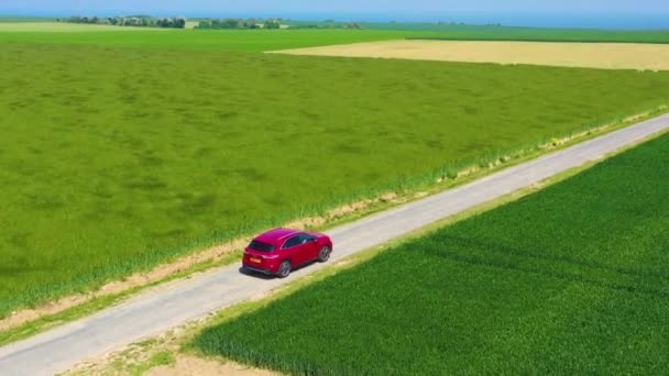 在法国诺曼底绿地间穿梭的一辆红色轿车的空中 — 图库视频影像