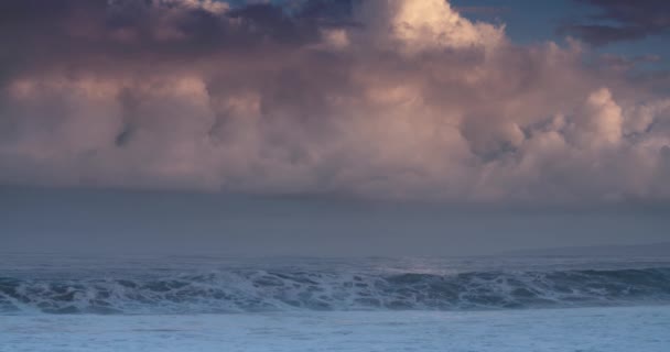 青い波は ピンクの雲の背景を持つゆっくりとした動きでハワイの海岸へと回転します — ストック動画