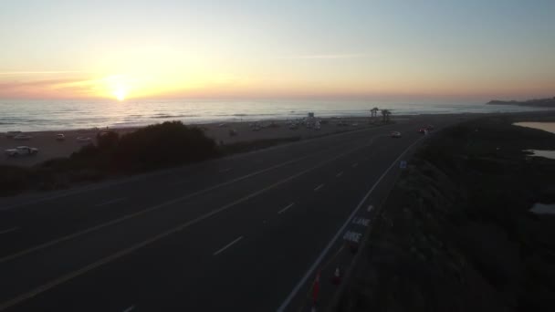 サンディエゴのカーディフ シーへの訪問者を歓迎する標識の上の航空機は日没時にビーチを明らかにする — ストック動画