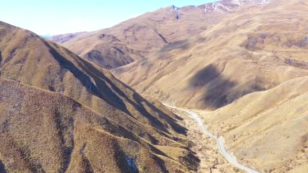 2019 ニュージーランドの南島の乾燥した山の風景を通って道路を走行する車の上空 — ストック動画