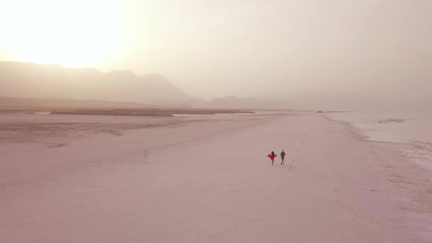 在一架模特儿的上空 一对情侣在吉布提海岸宽阔的沙滩上奔跑着 享受着欢乐 — 图库视频影像