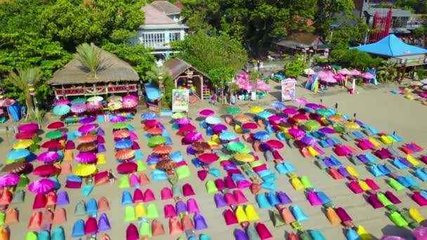 インドネシアのバリ島の海岸にあるサヌールまたはクタビーチのカラフルなビーチ傘の上に空中 — ストック動画
