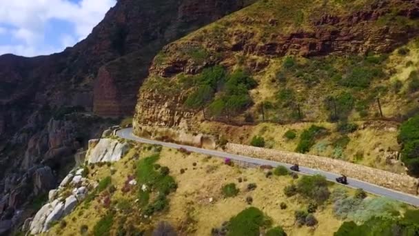 美しい海岸線と南アフリカのケープタウンの南の狭い道路を走行する2台のオートバイの空中 — ストック動画