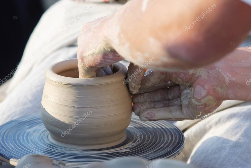 Pottery classes, student making clay pot on wheel.