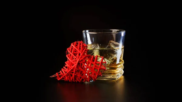 Corazones y vaso de alcohol sobre mesa negra — Foto de Stock