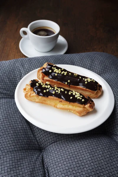 Weißer Teller mit Kaffee eclairs mit Tasse frischen schwarzen Kaffee — Stockfoto