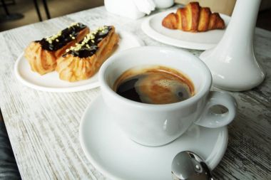 Kahve eklerleri ve kruvasan ile taze siyah kahve ile beyaz plaka