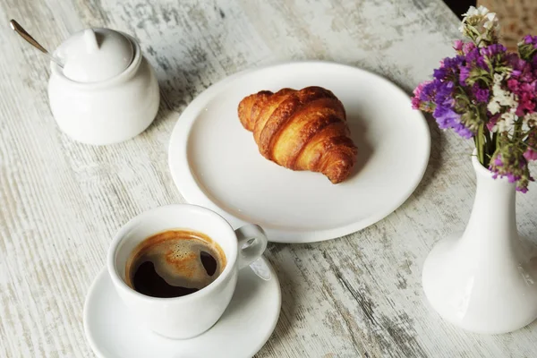Placa blanca con croissant con taza de café negro fresco — Foto de Stock