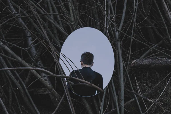 Человек перед зеркалом, отражающим его спину, темная концепция Лицензионные Стоковые Изображения