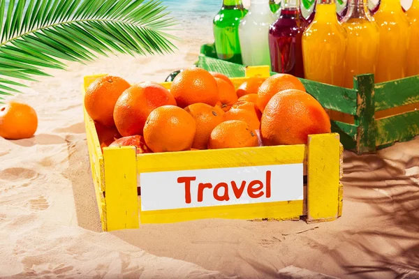 Orange trä låda och lemonad flaskor i soliga sommaren på stranden av havet med palmblad — Stockfoto