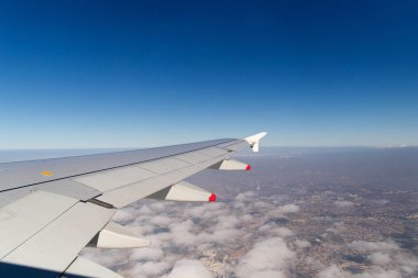 Bir uçak pencereden görüldüğü gibi gökyüzü ve bulutlar dağlar