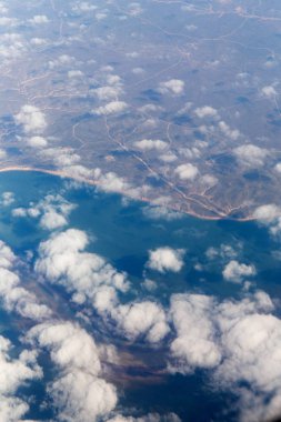 Bir uçak pencereden görüldüğü gibi gökyüzü ve bulutlar dağlar