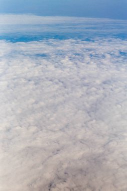 Bir uçak pencereden görüldüğü gibi gökyüzü ve bulutlar dağlar