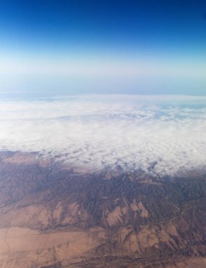 Bir uçak pencereden görüldüğü gibi gökyüzü ve bulutlar dağlar