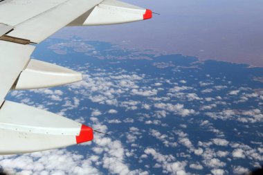 Bir uçak pencereden görüldüğü gibi gökyüzü ve bulutlar dağlar