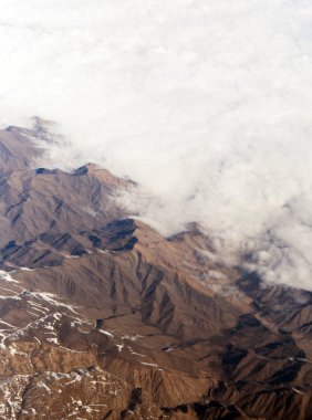 Bir uçak pencereden görüldüğü gibi gökyüzü ve bulutlar dağlar