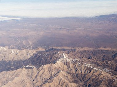 Bir uçak pencereden görüldüğü gibi gökyüzü ve bulutlar dağlar