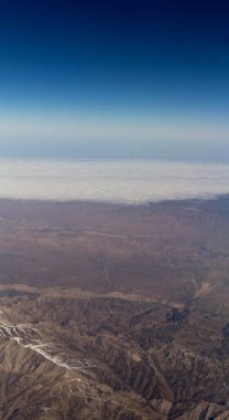 Bir uçak pencereden görüldüğü gibi gökyüzü ve bulutlar dağlar