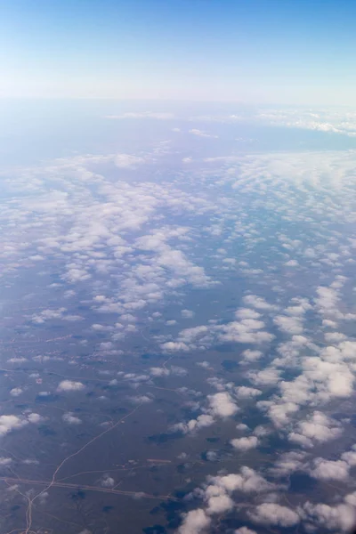 Nuages montagnes et ciel vus à travers la fenêtre d'un avion — Photo