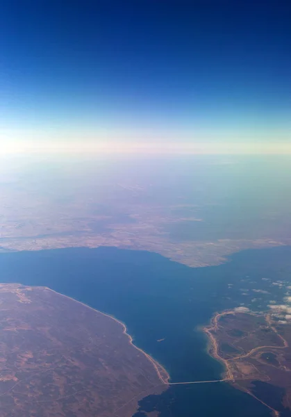 Nuages montagnes et ciel vus à travers la fenêtre d'un avion — Photo