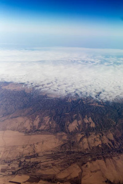 Molnen berg och himlen sedd genom fönstret på ett flygplan — Stockfoto