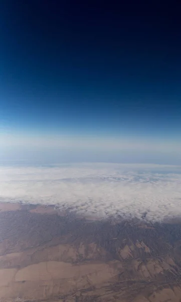 Nuvole montagne e cielo come visto attraverso la finestra di un aereo — Foto Stock