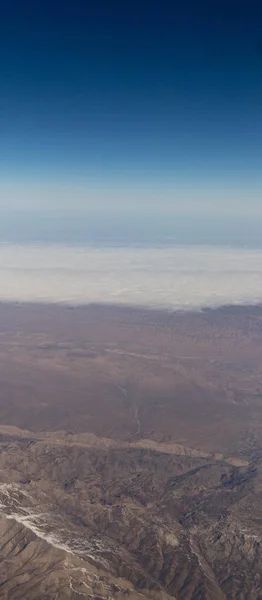 Nuvens montanhas e céu como visto através da janela de uma aeronave — Fotografia de Stock