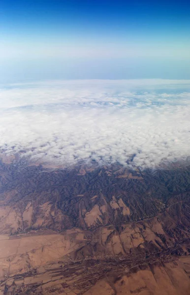 Mraky hory a nebe skrz okno letadla — Stock fotografie