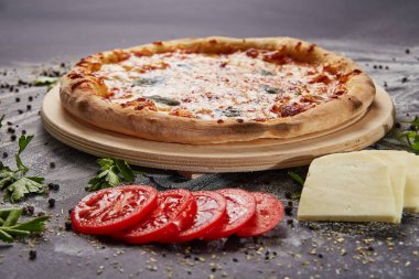 Bütün İtalyan lezzetli taze pizza domates ve biber karanlık bir arka plan üzerinde. Pizza siyah masada. maddeler ile