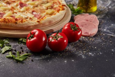 Bütün ve düzenlenen domates pizza İtalyan siyah kağıt masada