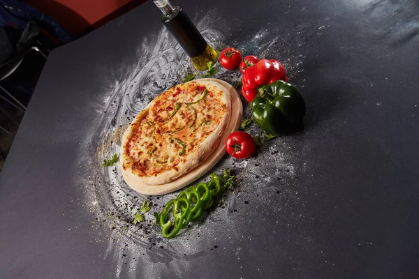 Hela den italienska pizza på bord av trä med ingredienser Royaltyfria Stockbilder