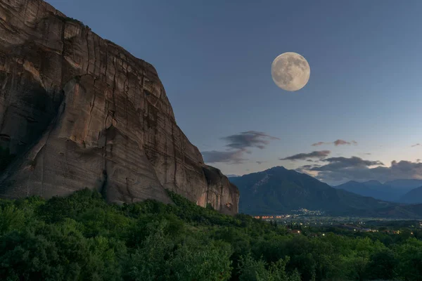 Rocky stone meteora and view at the Thessaly valley and mountains, twilight with full moon