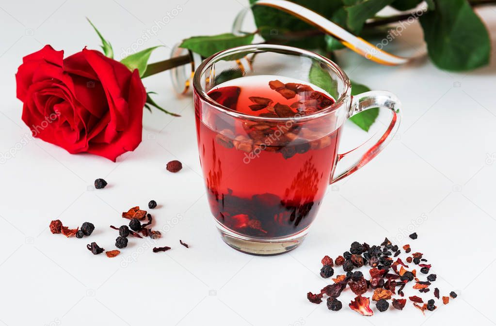 Herbal tea and red rose on white background