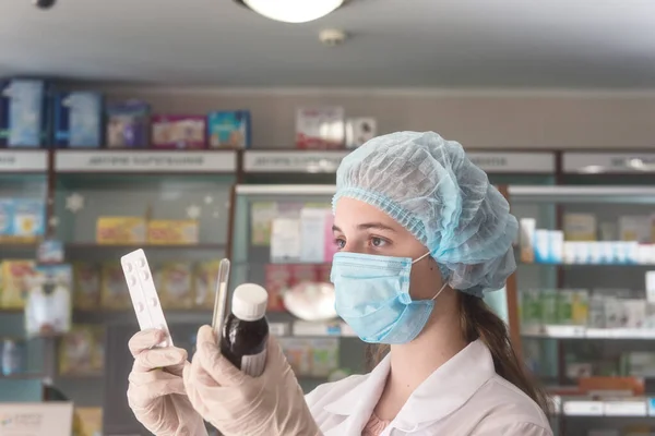 Koruyucu tıbbi maske takan, termometre ve ilaçlı genç bir kadın eczacı. Virüs kavramına karşı sağlık koruması. Seçici odaklı resim