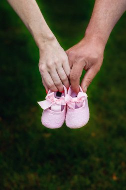First baby girl shoes in a parent hands`