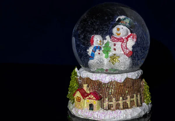 Bola de nieve de Navidad decorativa de primer plano con muñeco de nieve y copos de nieve — Foto de Stock