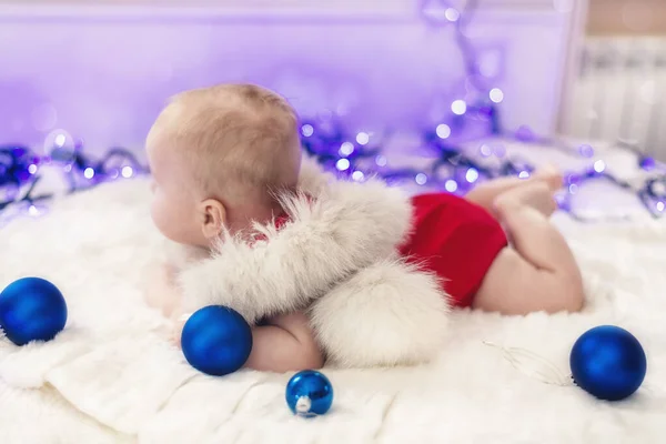Pequeno bebê em Santa suites deitado em uma barriga com atributos de celebração — Fotografia de Stock